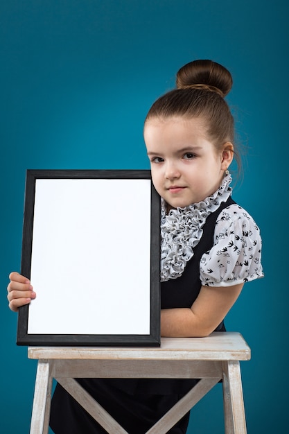 Isolated on blue, attractive caucasian child hold big empty poster