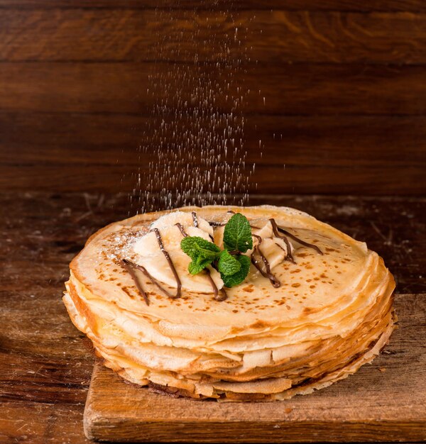 Isolated desert - stack of pancake with banana on a wooden table