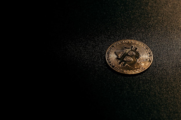 Isolated golden bitcoin on black background with reflection copy space