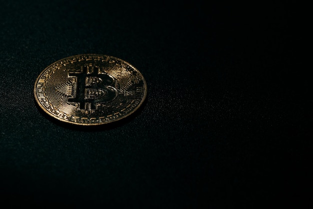 Isolated golden bitcoin on black background with reflection copy space