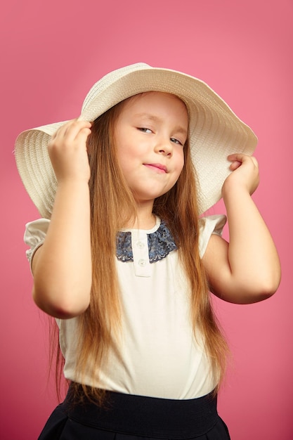 Isolated portrait of little girl in panama hat smile holds hand hat stands on pink isolated