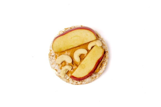 Isolated rice cake with peanut butter and slice of apple and cashew