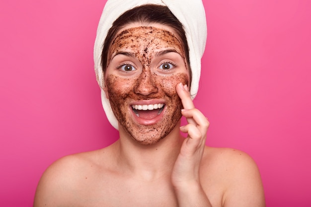 Isolated shot of surprised woman applies mask on face, has happy facial expresion, opens mouth from amezmant