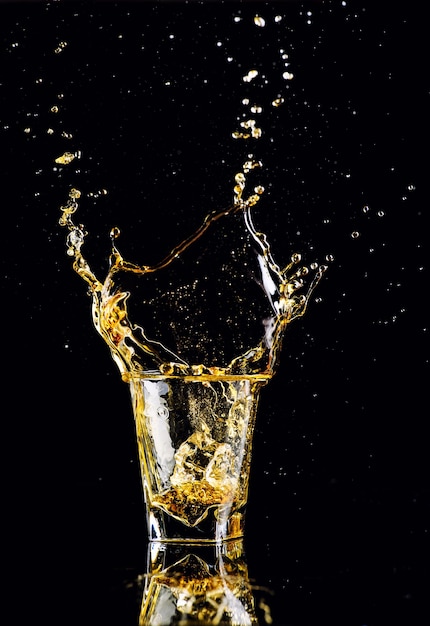 Isolated shot of whiskey with splash on black background brandy in a glass