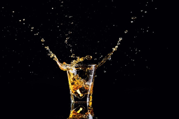 Isolated shot of whiskey with splash on black background brandy in a glass