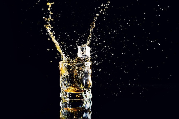 Isolated shot of whiskey with splash on black background brandy in a glass