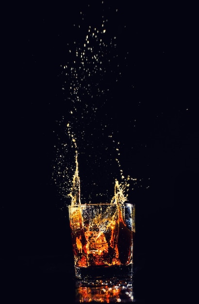 Isolated shot of whiskey with splash on black background brandy in a glass