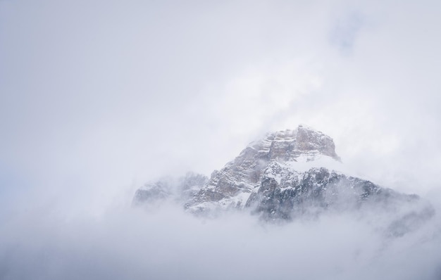 Isolated snowy alpine peak shrouded by clouds and fog yoho n park canada