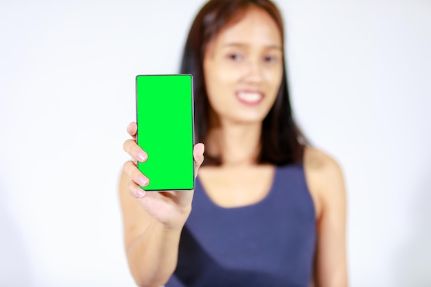 Isolated studio cutout shot of Asian young female teenager model in crop top shirt and jeans holding smartphone on white background