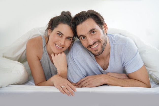 Isolated stunning couple looking at camera smiling in bed