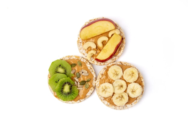 Isolated three rice cake meal with peanut butter kiwi slice banana and apple on white background