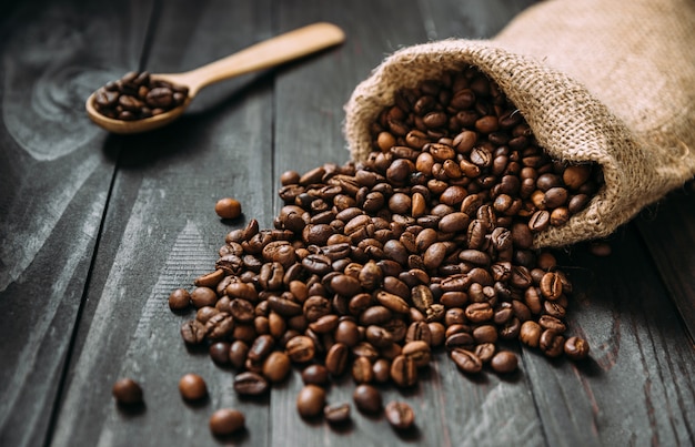 Isometric view of jute bag with spilled coffee beans on wooden table