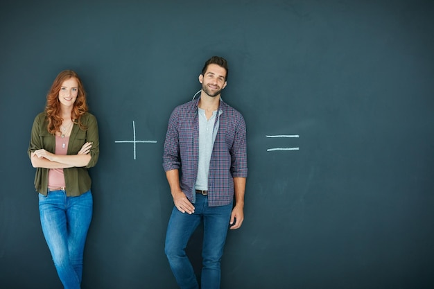 Photo it can only go one of two ways shot of a young couple standing in front of a blackboard with symbols written on it