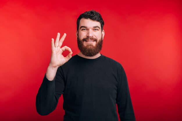 It's good Bearded man showing ok gesture on red wall.