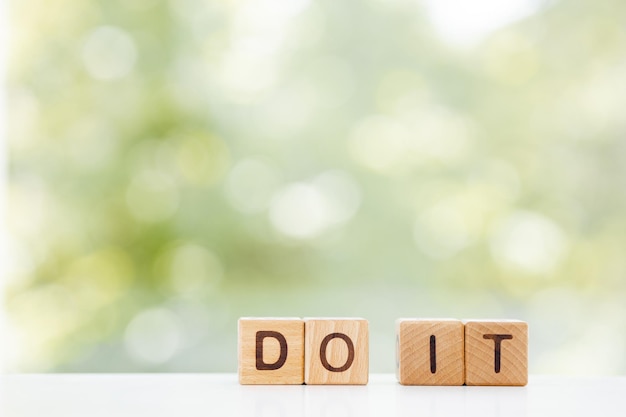 DO IT word on wooden cube over green summer background