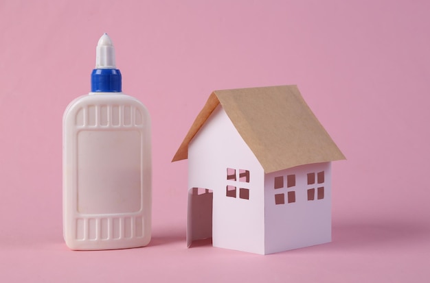 Do it yourself House model and glue bottle on pink background