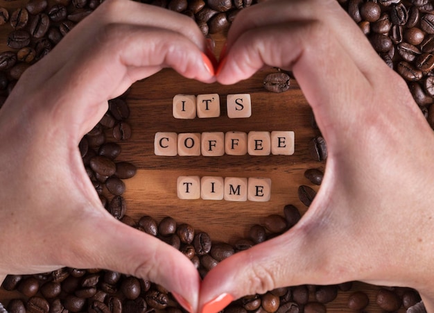 It39s coffee time with a wooden cube letters and woman making a heart with her hands