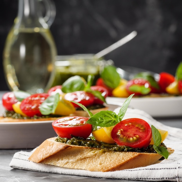 Italian antipasti bruschetta with tomato basil and pesto on a gray table Copy space