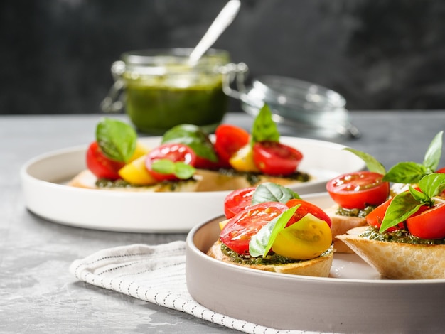 Italian antipasti bruschetta with tomato basil and pesto on a gray table Copy space