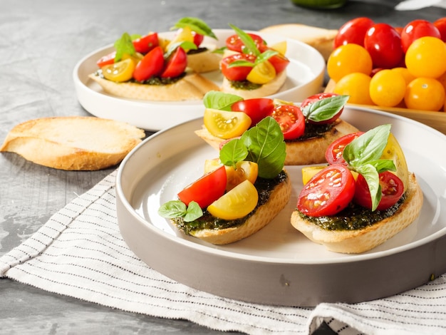 Italian antipasti bruschetta with tomato basil and pesto on a gray table Copy space