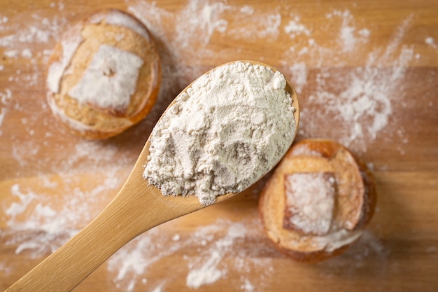 Italian bread with wooden spoon and wheat flour on wooden table