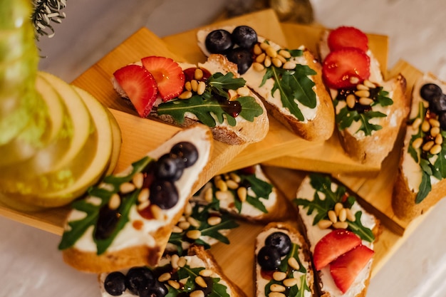 Italian bruschetta with cream cheese strawberry arugula and balsamic vinegar sauce with honey Appetizer with chiabatta bread and strawberry on wooden background Italian breakfast Italian cuisine