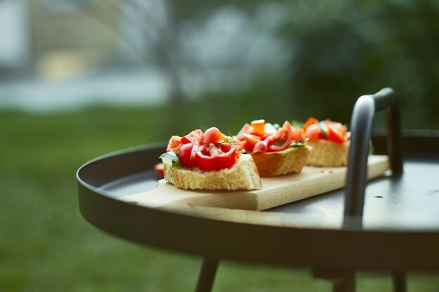 Italian bruschetta with fresh red tomatoes and basil herbs on a wooden board outdoor