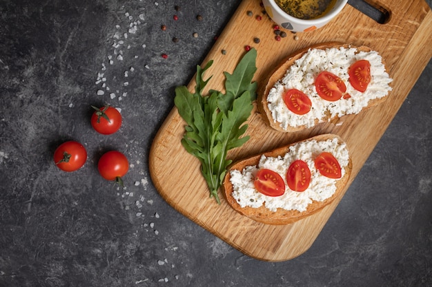 Italian bruschetta with roasted tomatoes, mozzarella cheese and herbs on a cutting board.