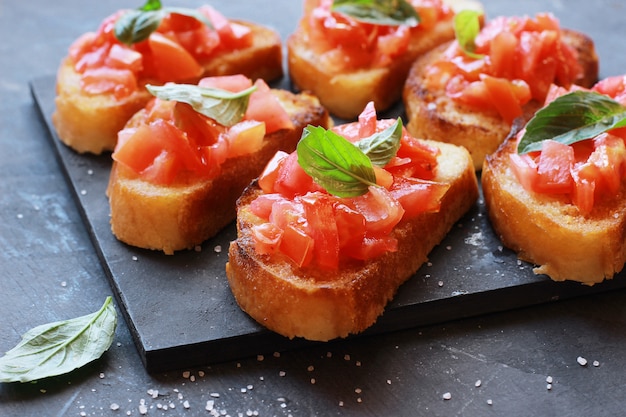 Italian bruschetta with tomatoes and basil on a black board