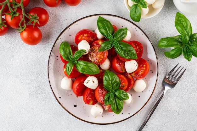 Italian caprese salad with sliced tomatoes mozzarella basil olive oil on a dark background Top view Italian food Healthy salad Summer food