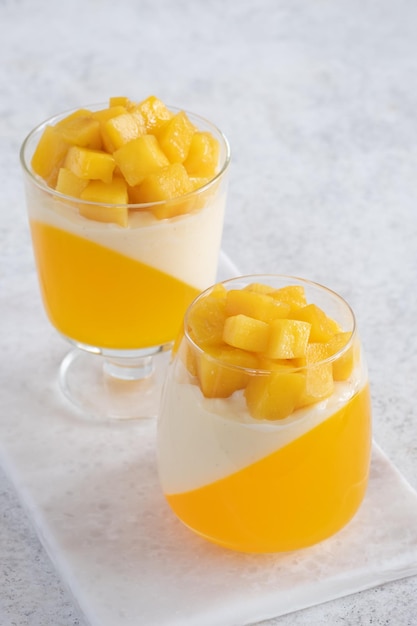 Italian dessert panna cotta with mango jelly and pieces of fresh mango