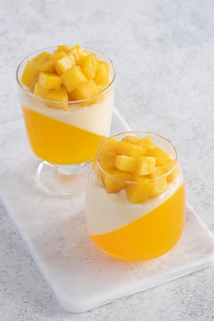 Italian dessert panna cotta with mango jelly and pieces of fresh mango