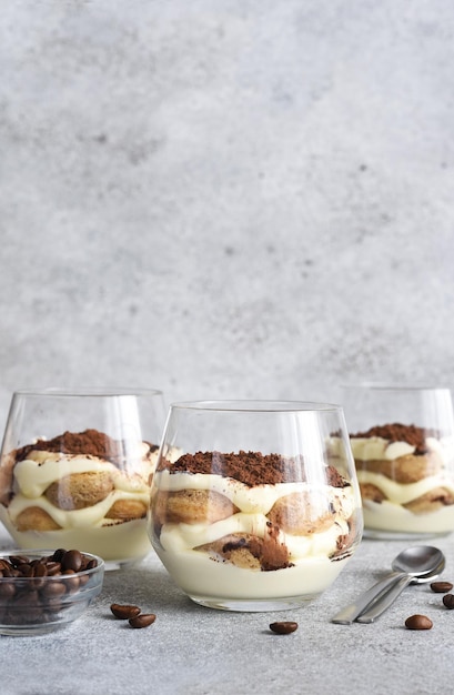 Italian dessert tiramisu in a glassxAClassic tiramisu with coffee on a concrete background