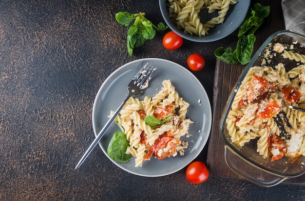 Italian dish of  pasta mixing with Feta cheese baked and tomatoes on a dark background. Fetapasta. Trending viral recipe, Flat lay, copy space