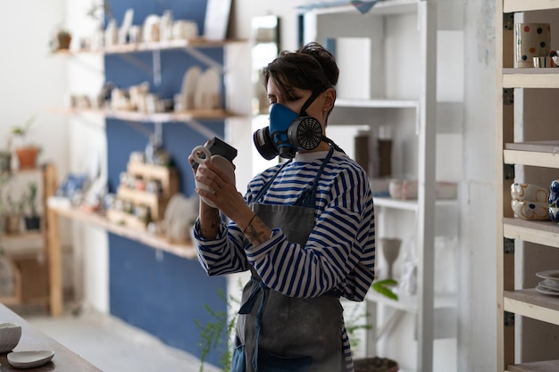 Italian female ceramic artist polishing pottery in studio smoothing the surface of clay object