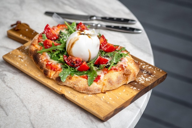 Italian focaccia with burrata and zucchini flower with tomatoes cherry and ham flatlay top view composition on a black background