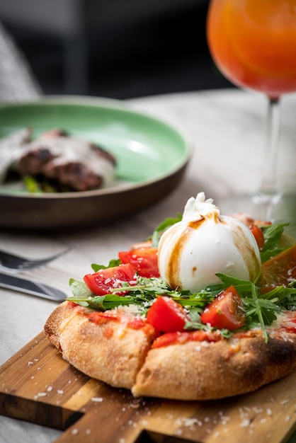 Italian focaccia with burrata and zucchini flower with tomatoes cherry and ham flatlay top view composition on a black background