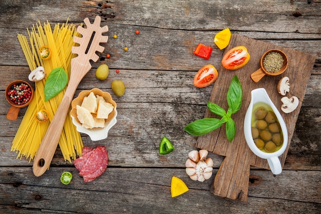 Italian food cooking ingredients on shabby wooden background with flat lay and copy space.