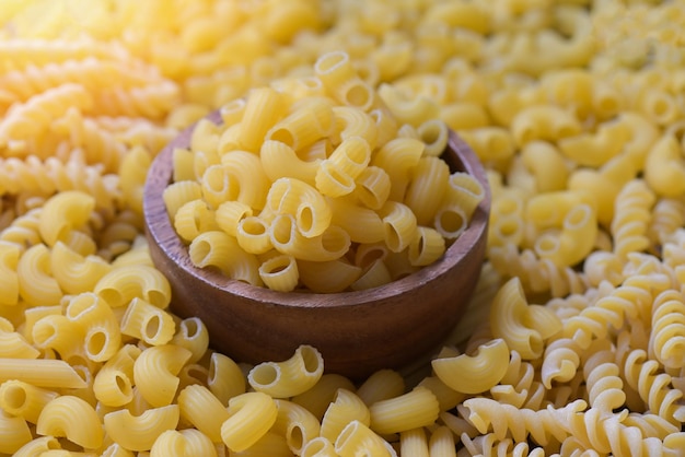 Italian food culinary concept raw pasta for cooking food raw macaroni on wooden bowl pasta various kinds of uncooked pasta spaghetti and noodles on background