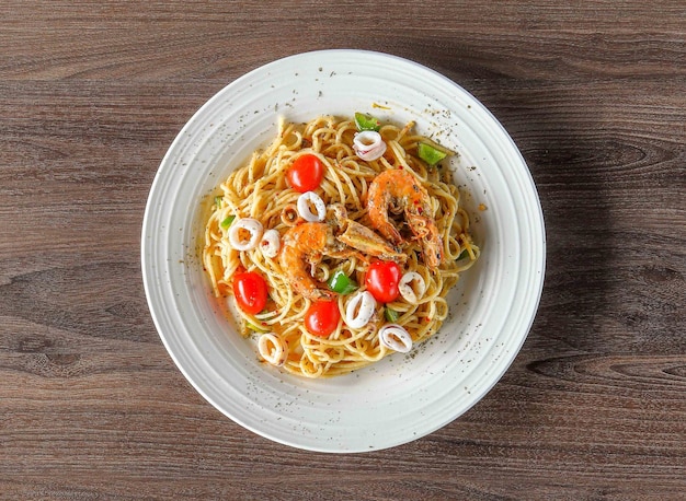 Italian food Prawn Aglio Olio pasta noodle with black pepper in a dish on wooden board top view on w