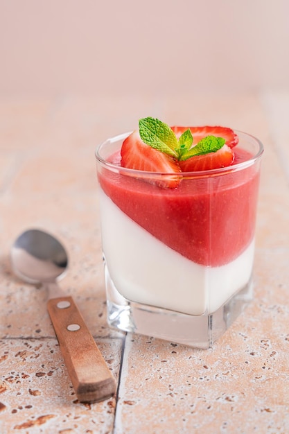 Italian homemade panna cotta sweet dessert with strawberry sauce and topping of fresh red berries