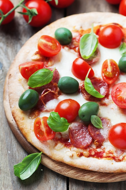 Italian hot pizza with salami, olive and tomato