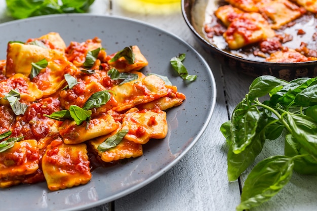 Italian or mediterranean food pasta ravioli of tomato sauce and basil.