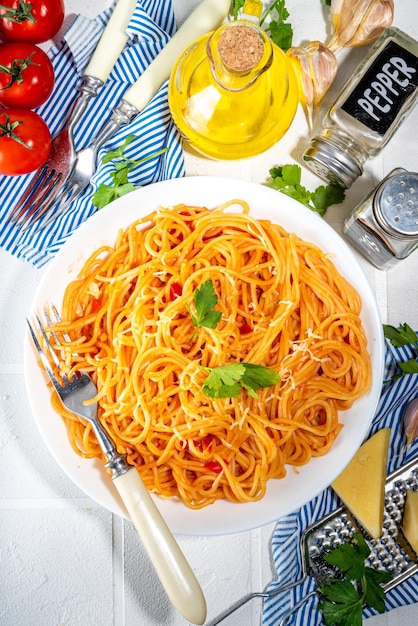 Italian mediterranean lunch concept Spaghetti pasta with marinara tomato sauce On a white tile table with spices for dinner copy space