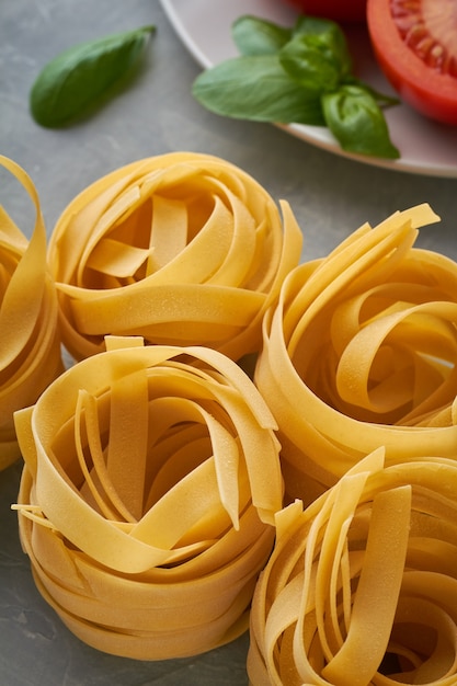 Italian pasta fettuccine with tomato olive oil basil on grey background