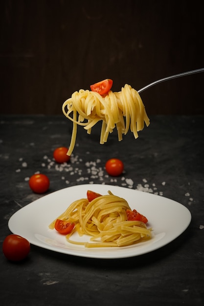 Italian pasta on a plate on a dark  with cherry tomatoes