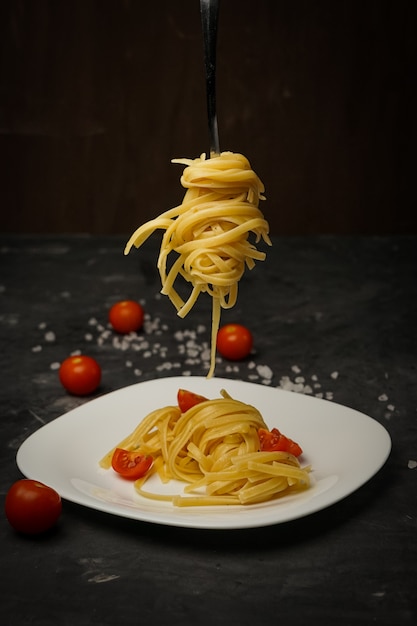 Italian pasta on a plate on a dark  with cherry tomatoes