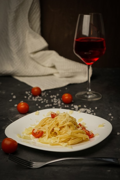 Italian pasta on a plate on a dark  with cherry tomatoes