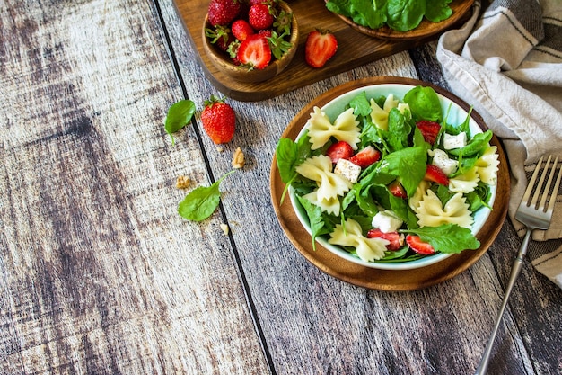 Italian pasta salad with strawberries arugula nuts soft cheese dressed Copy space