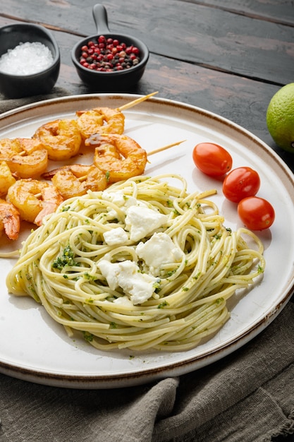 Italian pasta spaghetti with grilled shrimps, pesto sauce set, on plate, on old dark  wooden table background